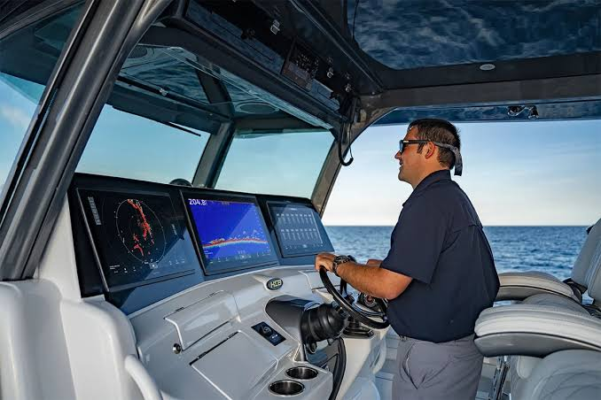 Skipper at the helm of an Argus setup with radar, sounder and systems displays underway
